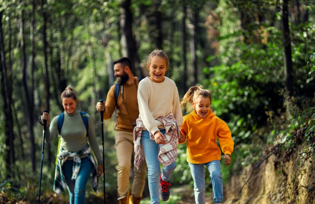 Smiling family of four enjoying hiking in trough forest.